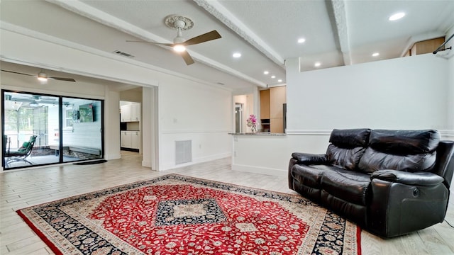 living room featuring beamed ceiling, light wood-type flooring, and visible vents