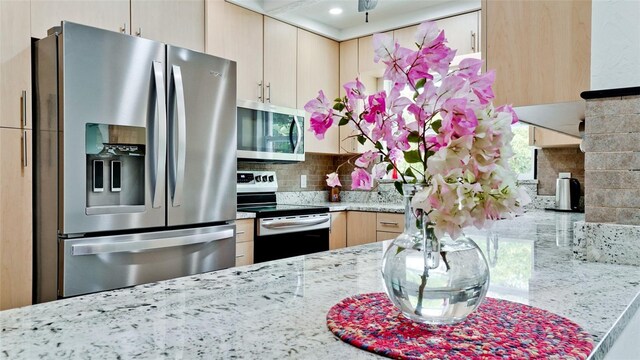 kitchen with light stone countertops, tasteful backsplash, stainless steel appliances, ceiling fan, and light brown cabinets