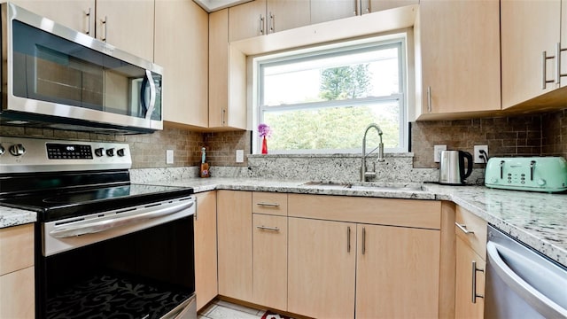 kitchen with stainless steel appliances, light brown cabinets, and a sink