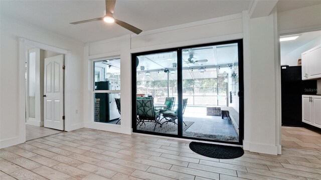 doorway with light wood-type flooring and ceiling fan