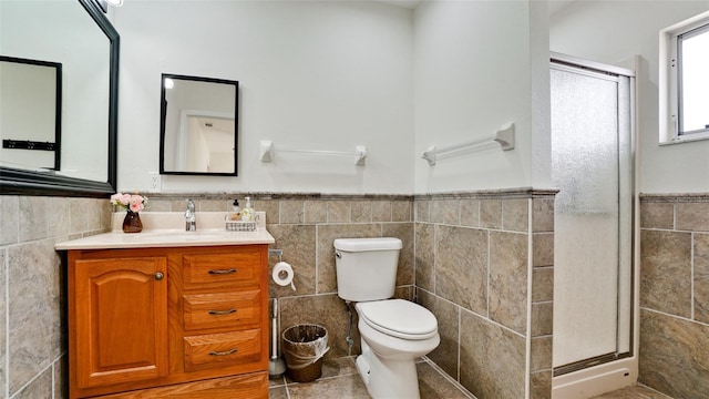 bathroom featuring toilet, a stall shower, vanity, and tile walls