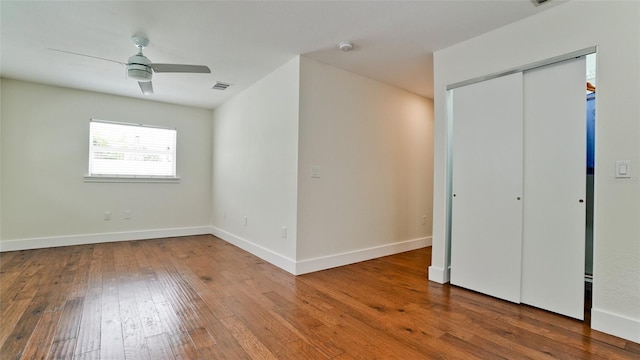 unfurnished bedroom with wood finished floors, a ceiling fan, visible vents, baseboards, and a closet