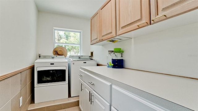 washroom featuring wainscoting, independent washer and dryer, and cabinet space