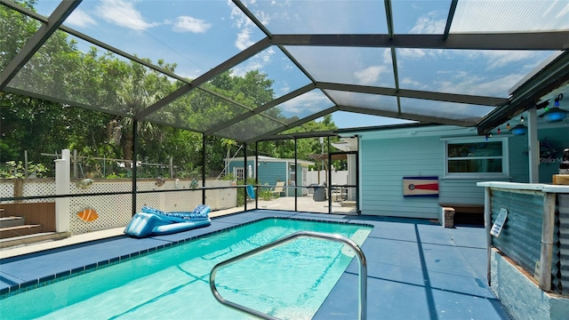 view of swimming pool featuring a fenced in pool, glass enclosure, an outbuilding, a storage unit, and a patio area