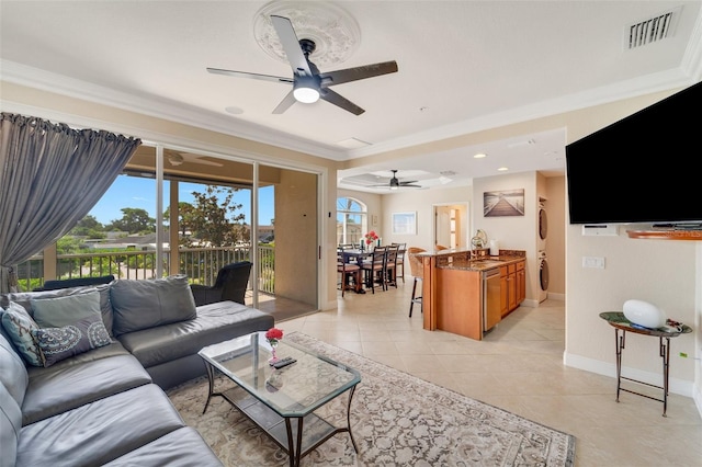 living room with stacked washer / drying machine, crown molding, and ceiling fan