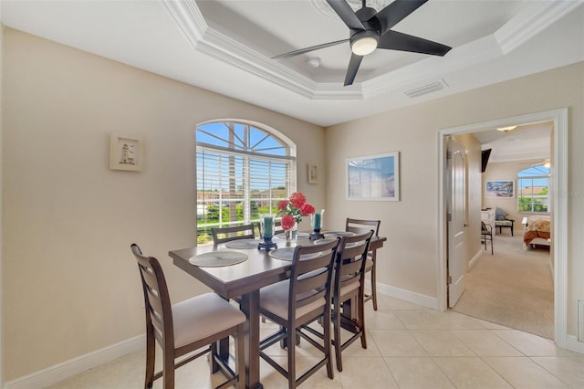 dining space with light tile patterned flooring, a healthy amount of sunlight, a tray ceiling, and ceiling fan