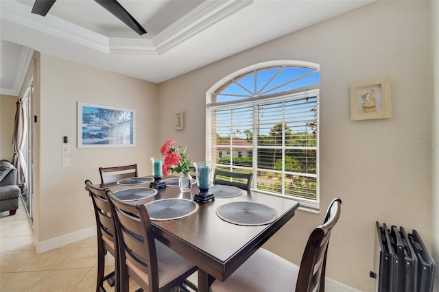 dining area with light tile patterned flooring, ornamental molding, and a tray ceiling