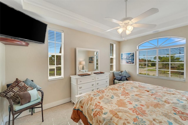 carpeted bedroom with ceiling fan and a tray ceiling