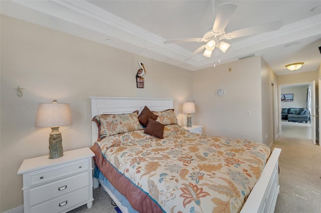 carpeted bedroom featuring a tray ceiling and ceiling fan