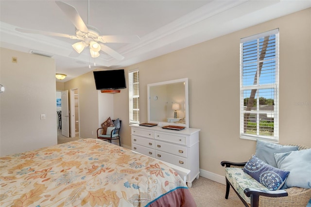 carpeted bedroom with ceiling fan and a raised ceiling