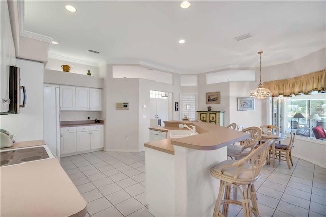 kitchen with light tile patterned floors, white cabinetry, hanging light fixtures, and sink