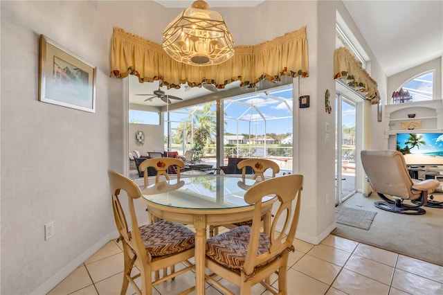 tiled dining room with a healthy amount of sunlight and ceiling fan with notable chandelier