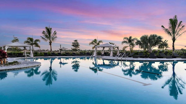 pool at dusk featuring a gazebo