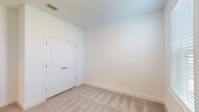 unfurnished bedroom with light carpet and a closet