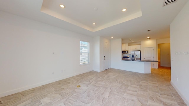 unfurnished living room with a raised ceiling and sink