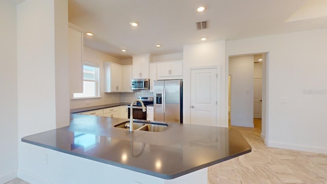 kitchen with kitchen peninsula, appliances with stainless steel finishes, backsplash, sink, and white cabinets