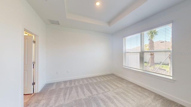 carpeted empty room featuring a tray ceiling