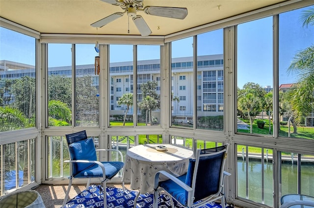 sunroom / solarium featuring a water view and a ceiling fan