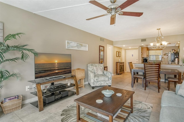 living room featuring ceiling fan with notable chandelier, visible vents, baseboards, and light tile patterned floors