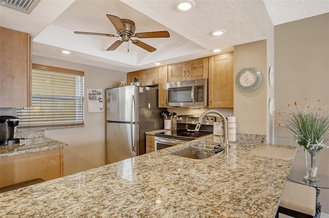 kitchen featuring stainless steel appliances, a raised ceiling, visible vents, and light stone countertops