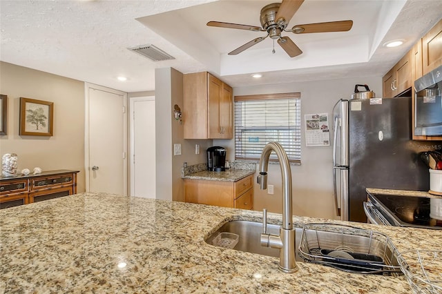 kitchen featuring stainless steel appliances, visible vents, a sink, ceiling fan, and light stone countertops