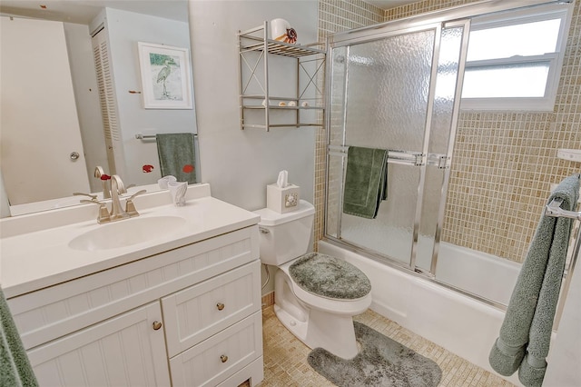 bathroom with toilet, tile patterned floors, combined bath / shower with glass door, and vanity