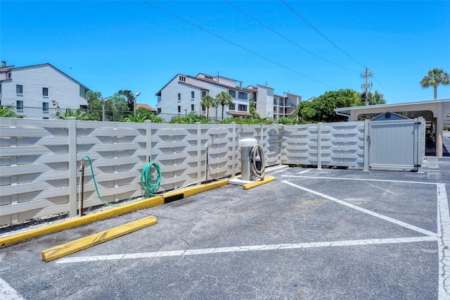 view of vehicle parking featuring fence and a gate