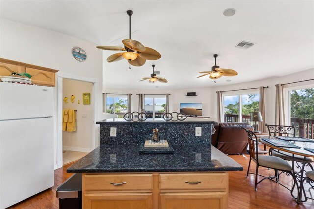 16361 Stringfellow Rd, Bokeelia, FL 33922 - kitchen featuring freestanding refrigerator, a kitchen island, wood finished floors, a ceiling fan, and dark stone counters