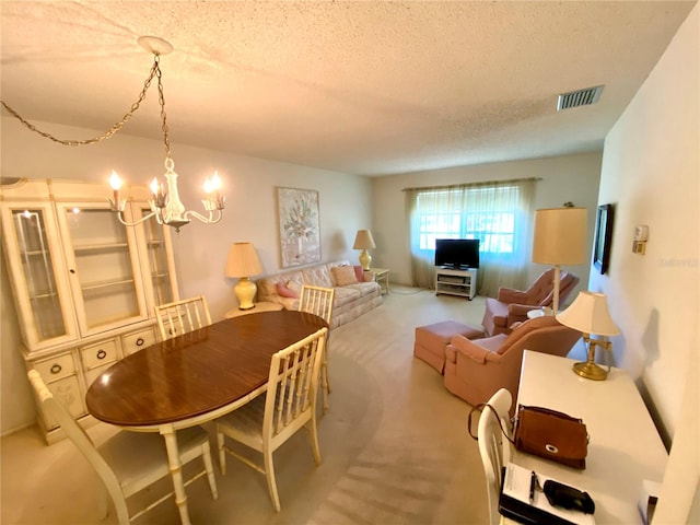 dining room with an inviting chandelier, light colored carpet, and a textured ceiling