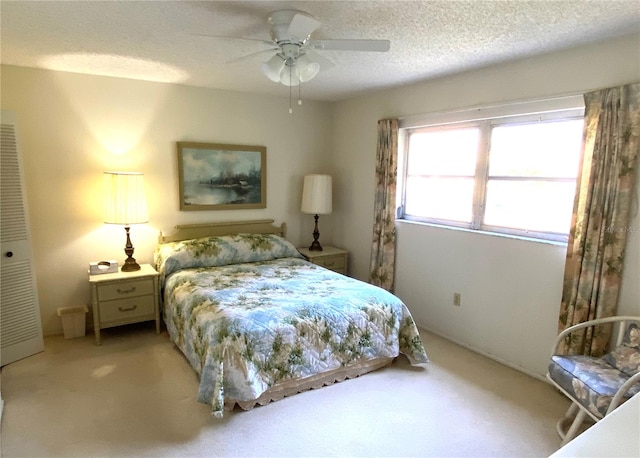 bedroom featuring light carpet, ceiling fan, and a textured ceiling