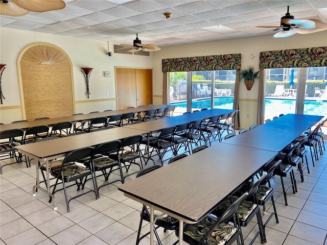 dining area with ceiling fan, a paneled ceiling, and light tile patterned floors