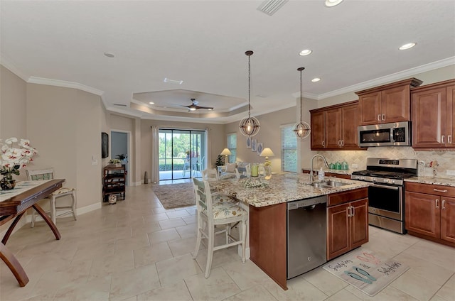 kitchen featuring ceiling fan, sink, a raised ceiling, a center island with sink, and appliances with stainless steel finishes