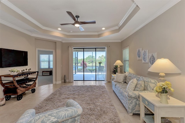 tiled living room featuring a tray ceiling, ceiling fan, and ornamental molding