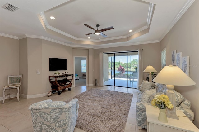 living room featuring light tile patterned floors, crown molding, and a tray ceiling