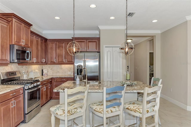 kitchen featuring a kitchen breakfast bar, decorative light fixtures, stainless steel appliances, and a kitchen island with sink