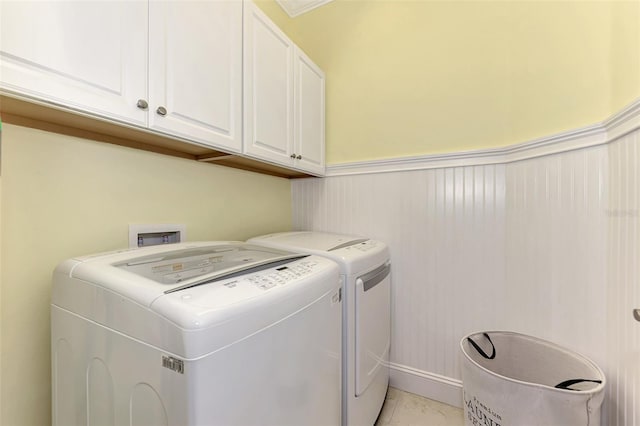 laundry room with cabinets, light tile patterned floors, and washing machine and clothes dryer