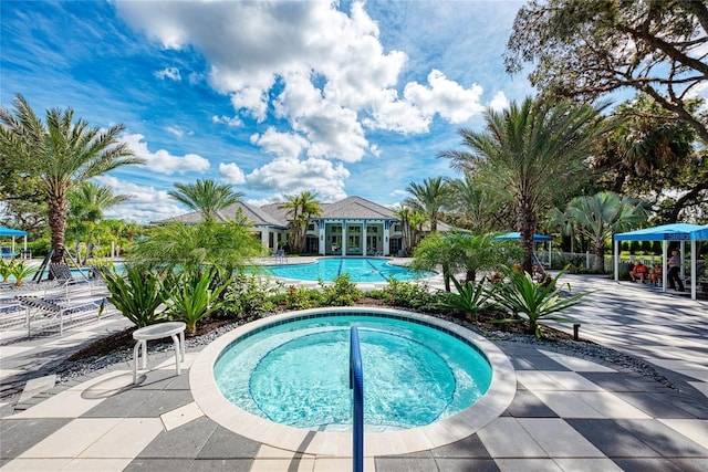 view of pool with a hot tub and a patio area