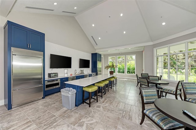 kitchen with blue cabinets, a breakfast bar, a center island, and appliances with stainless steel finishes