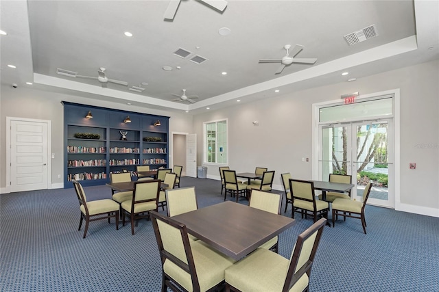 dining space featuring ceiling fan, dark carpet, and a raised ceiling