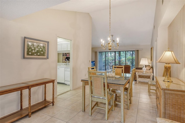 dining area featuring a notable chandelier, light tile patterned floors, sink, and high vaulted ceiling