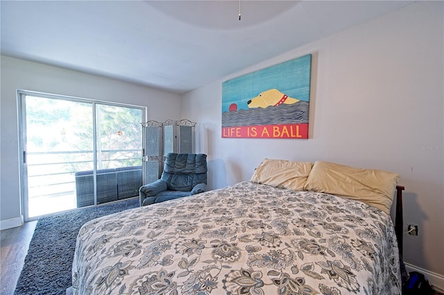 bedroom featuring access to outside, wood finished floors, and baseboards