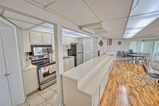 kitchen with stainless steel appliances, a paneled ceiling, light countertops, visible vents, and white cabinetry