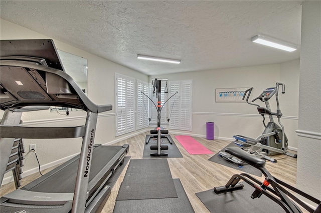 workout area with a textured ceiling, baseboards, and wood finished floors