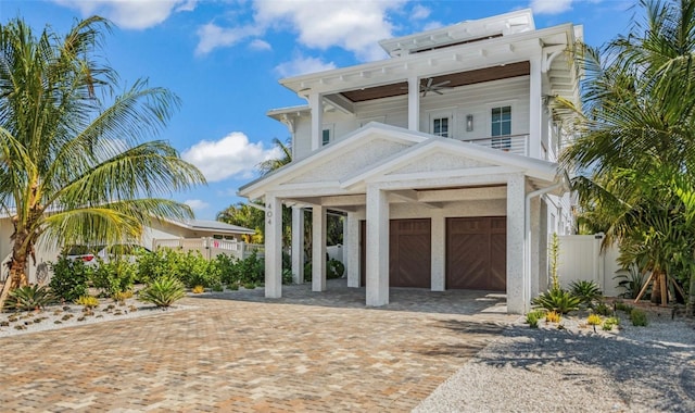 view of front of property featuring a carport, ceiling fan, a garage, and a balcony