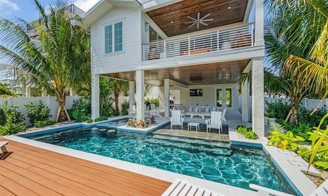 rear view of property featuring a pool side deck, ceiling fan, and a balcony