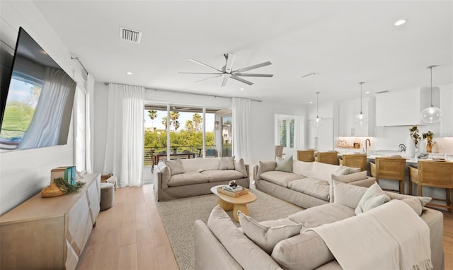 living room with ceiling fan, light wood-type flooring, and sink