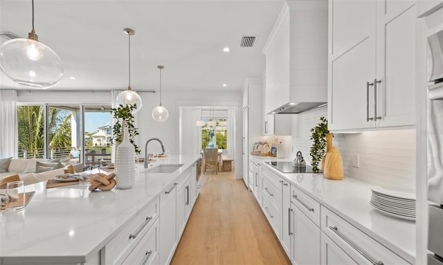 kitchen featuring pendant lighting, sink, a wealth of natural light, and wall chimney range hood