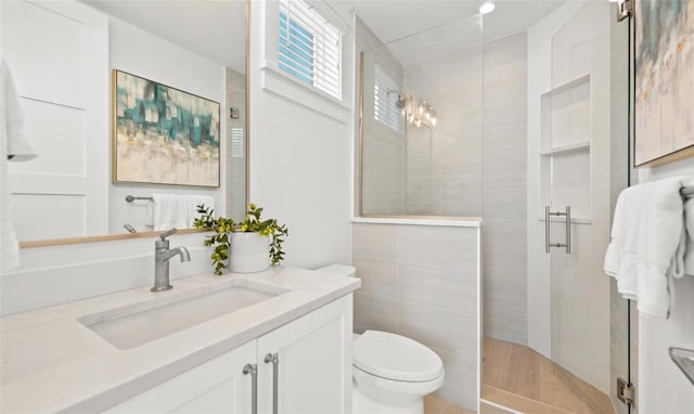 bathroom featuring vanity, toilet, a shower with door, and tile walls