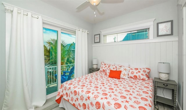 bedroom with access to outside, ceiling fan, wood-type flooring, and wood walls