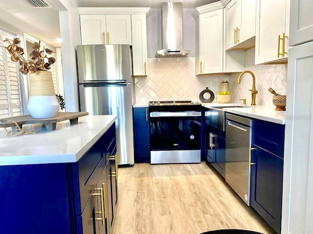 kitchen with stainless steel appliances, light wood-type flooring, backsplash, wall chimney range hood, and white cabinets